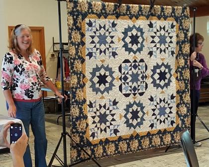 Jodi and Elaine reveal next year's quilt. It commemorates Nebraska statehood
